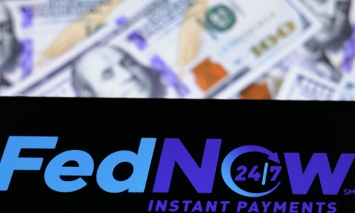 FedNow Service logo seen displayed on a smartphone with hundred dollar bills in background