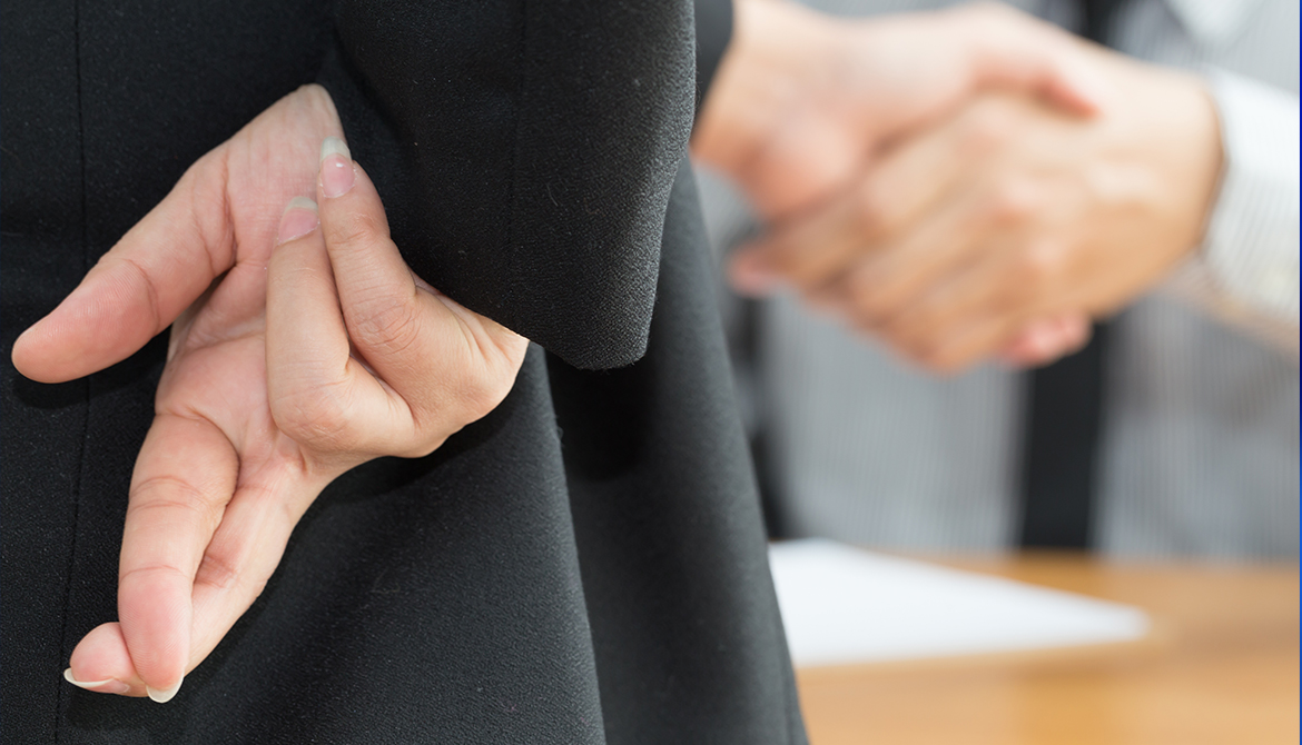 Businessman showing fingers crossed behind his back while he shakes hands