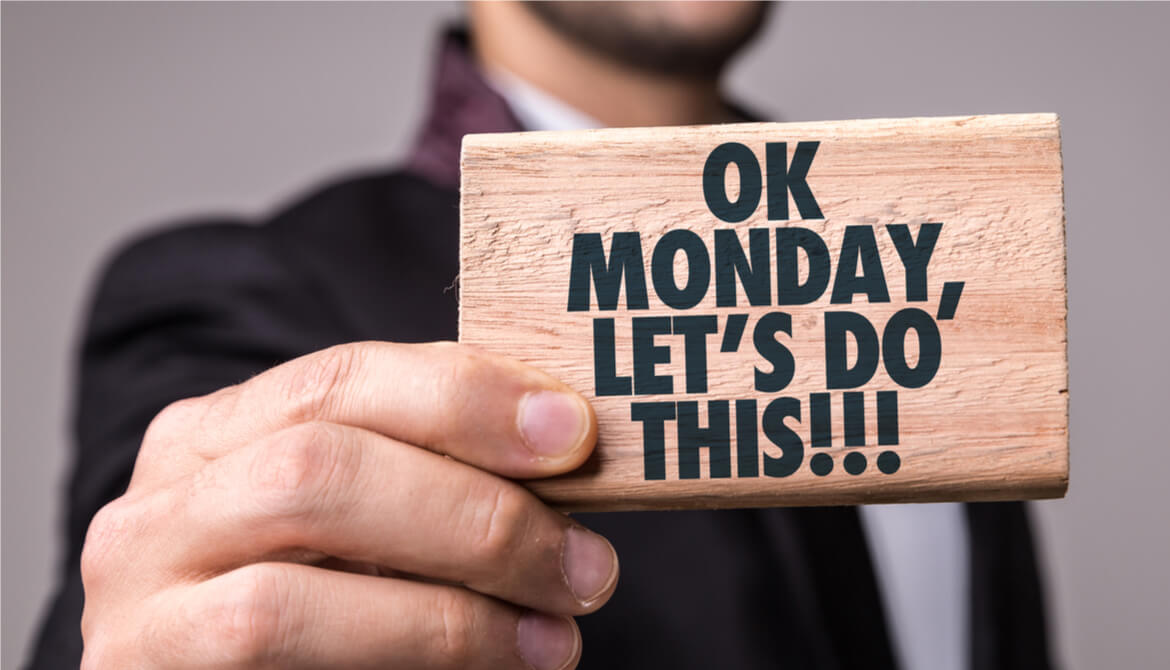 man holds sign that says Ok Monday Lets Do This