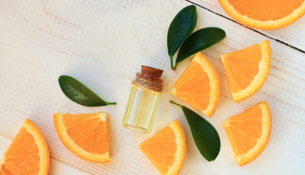 orange slices with a vial of essential oil and fragrant leaves