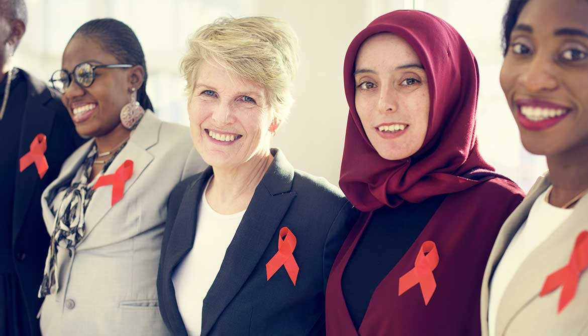 diverse group of women standing shoulder to shoulder wearing orange partnership ribbons