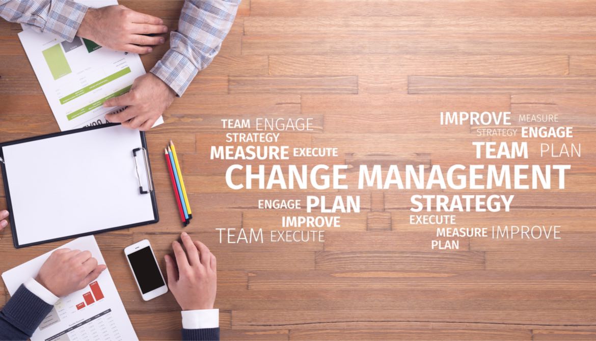 people working together with words about change management on wooden table
