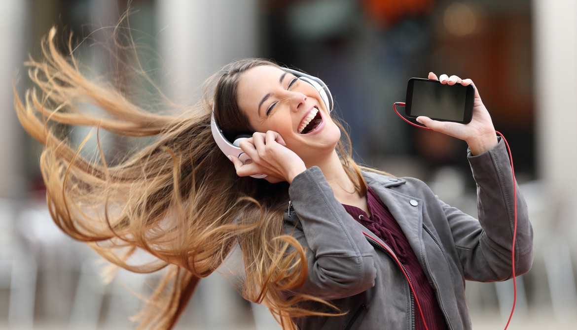 young woman dancing with cell phone and hair flying