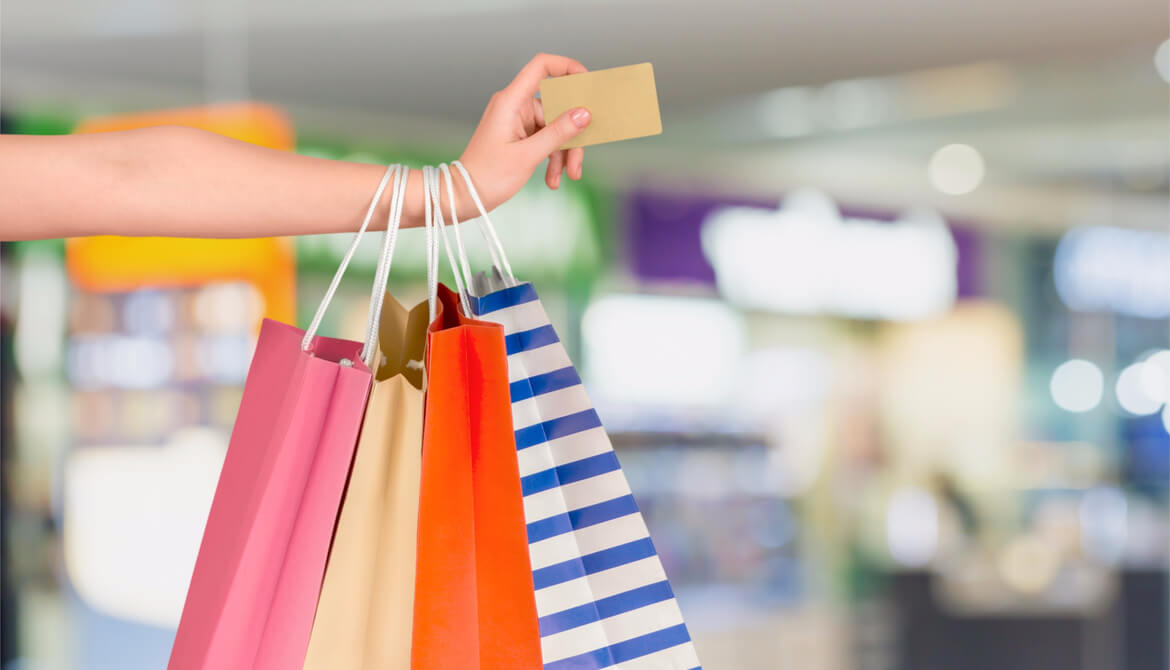 woman with several colorful shopping bags holding credit card