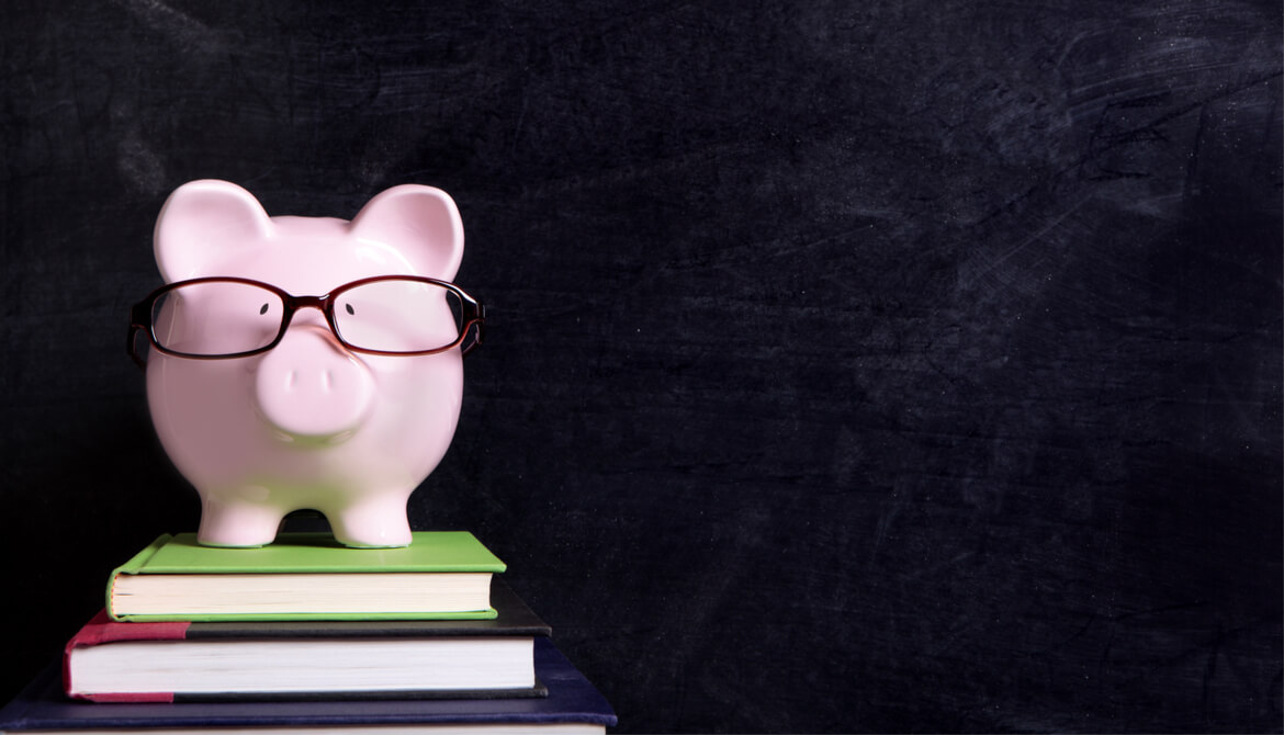 piggybank wearing glasses standing on a stack of books