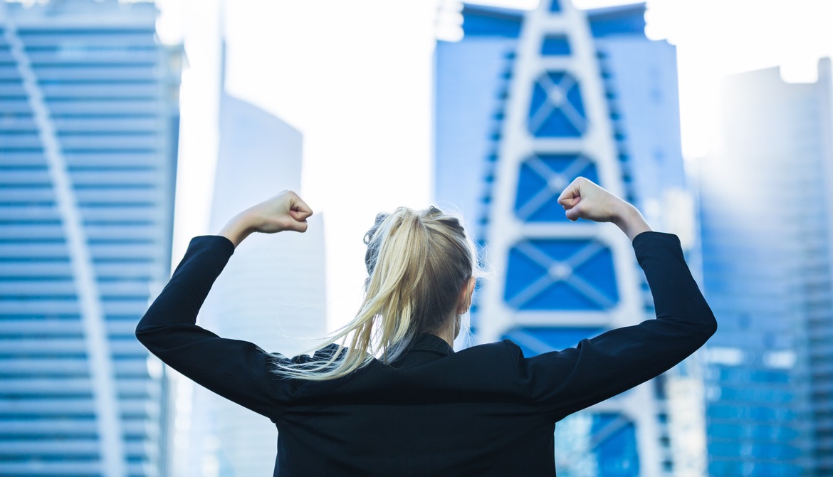 energetic female business leader flexes in front of cityscape