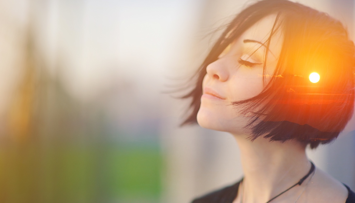 sunset superimposed on image of woman with eyes closed taking deep meditative breath to release stress