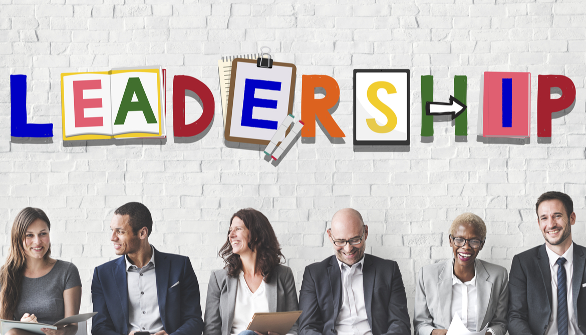 diverse group of business people sitting against a wall with the word Leadership
