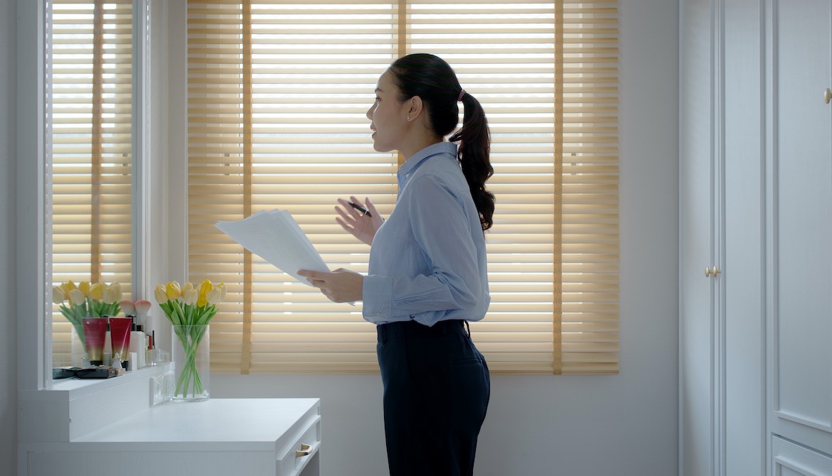 young Asian businesswoman practices presentation in front of bathroom mirror 