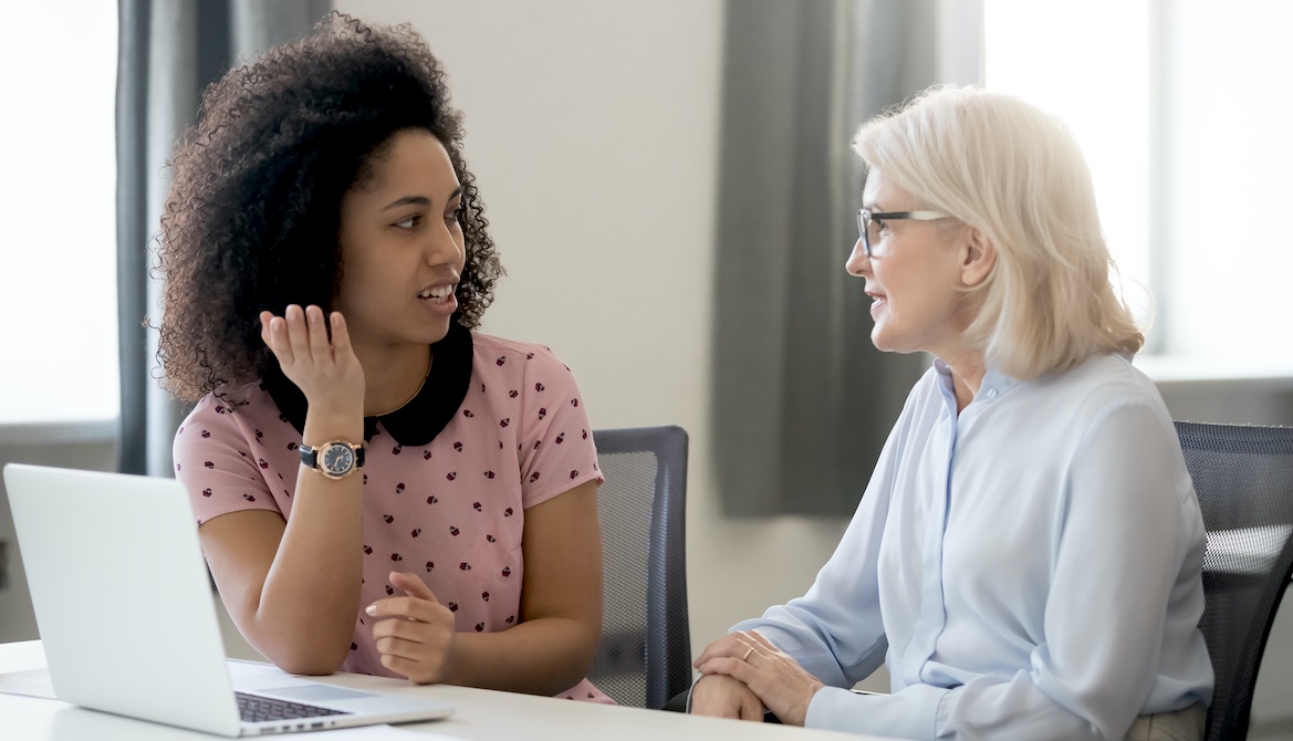 older white woman mentors younger Black woman at the office