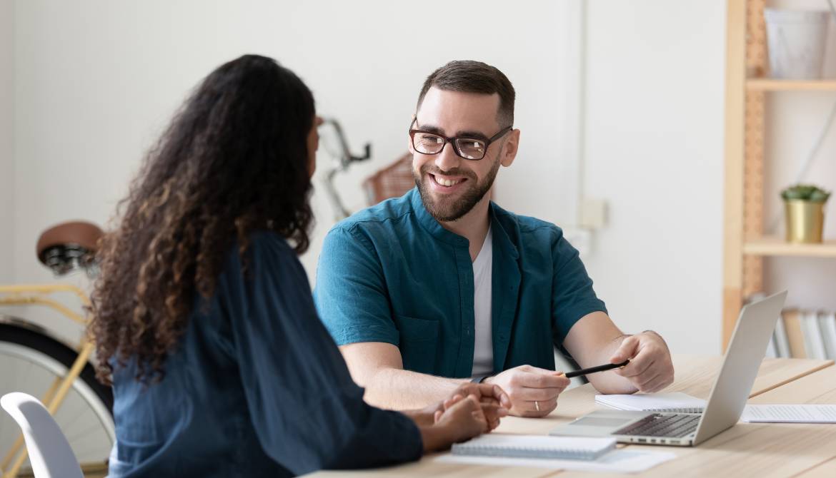 smiling male and female coworkers brainstorm together at desk