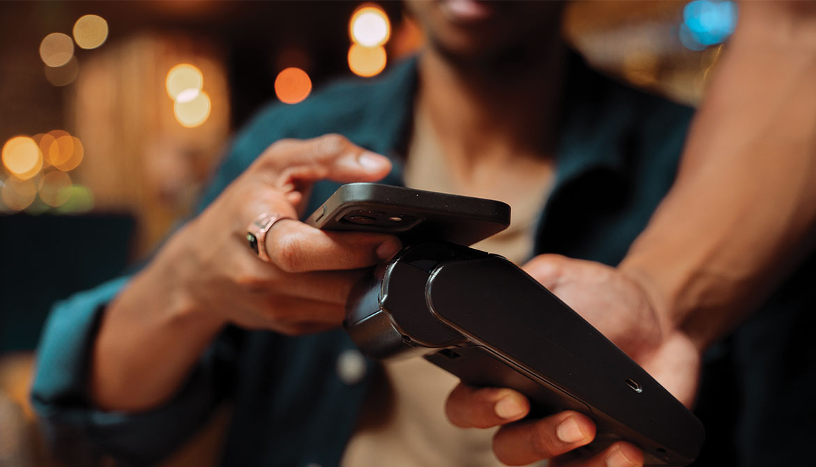 customer holds out smartphone to tap wireless payment device in a restaurant