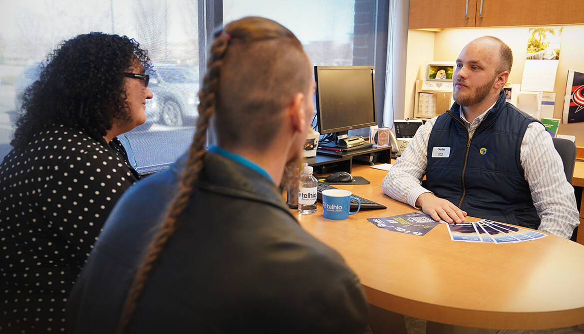 a couple speaking with a Telhio employee at his desk