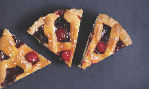 three pieces of cherry pie on a gray backdrop, one slightly smaller than the other two
