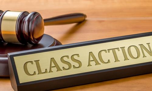 Gavel laying on a desk next to a brass plaque that reads class action