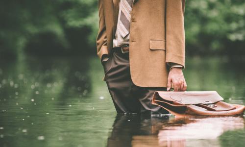 Businessman stands in flood with briefcase