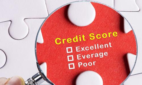 a magnifying glass focusing on the words credit score on a puzzle piece in a larger white puzzle