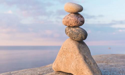 a cairn or stack or rocks on a beach with a beautiful blue sky