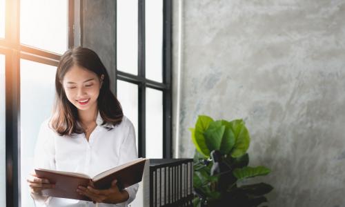 young Asian businesswoman reading by office window
