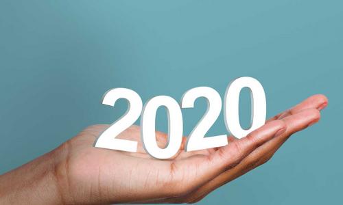 White 2020 year numbers in woman's hand on blue background