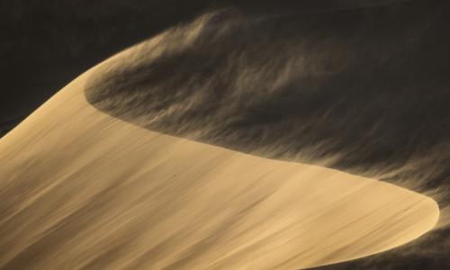 wind blowing across sand dunes