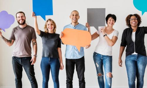 diverse employees standing holding up paper conversation bubbles of different shapes and sizes