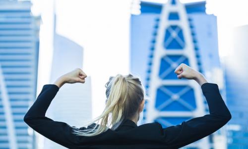 energetic female business leader flexes in front of cityscape