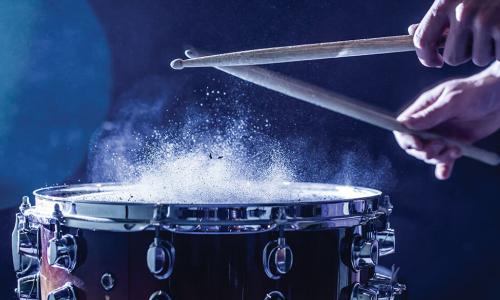 dust puffing upward as drummer hits snare drum with sticks