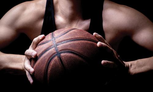 muscular athlete holding basketball in both hands preparing to pass
