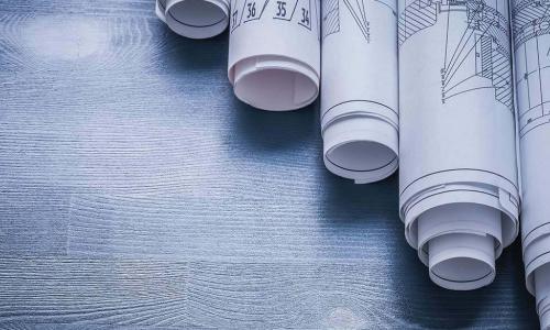 rolled up architectural blueprints on wooden table