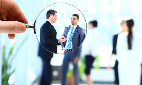 magnifying glass brings potential executive candidates into focus in the midst of a blurry view of a group of businesspeople