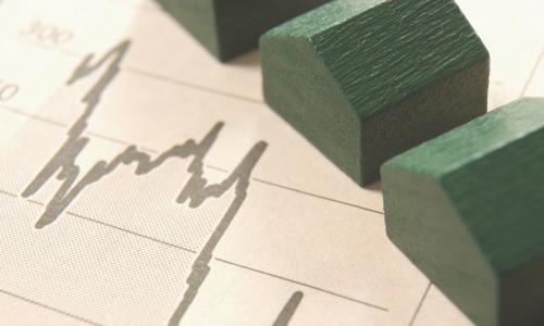 miniature green wooden houses on a balance sheet chart