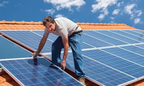 roofer installing solar panels on a terra cotta tile roof