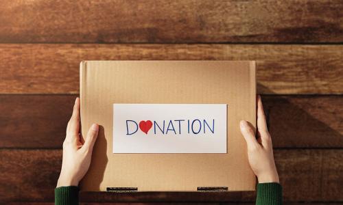 hands holding out a box labeled DONATION with a heart on it