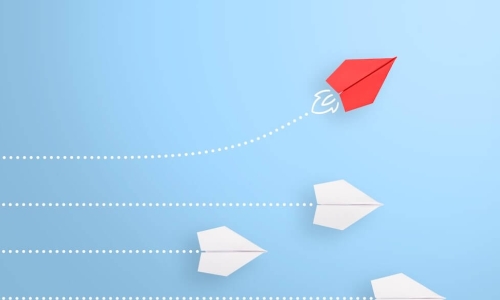 one red paper airplane flying it's own course away from 3 white paper airplanes