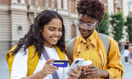 2 students looking at a smartphone and a credit card