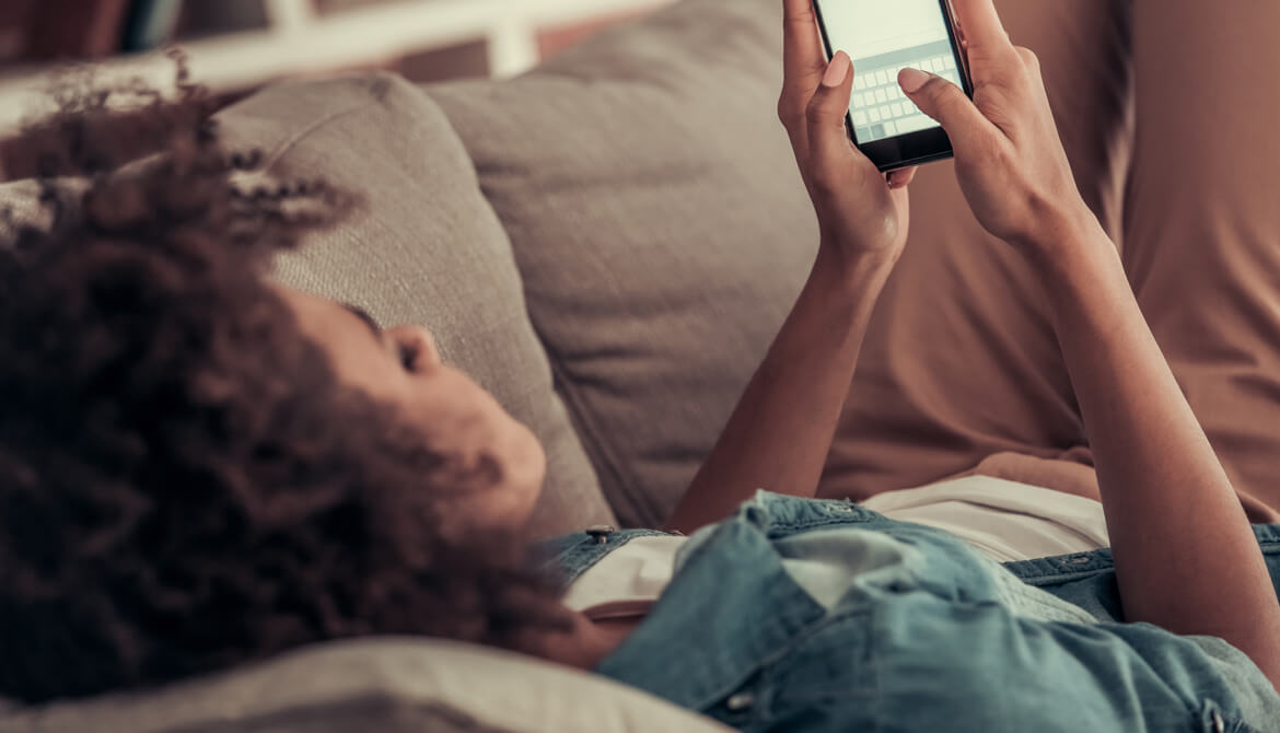 young person on couch with smart phone