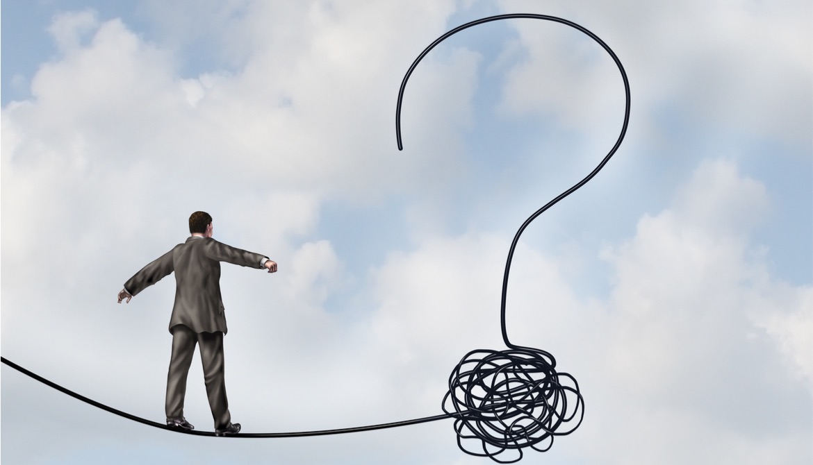 businessman walking tight rope toward a question mark in the air