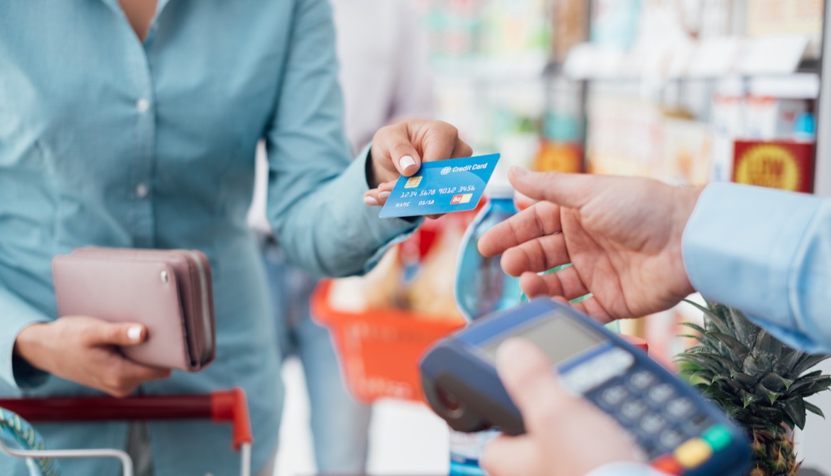Woman at the supermarket checkout paying using a credit card