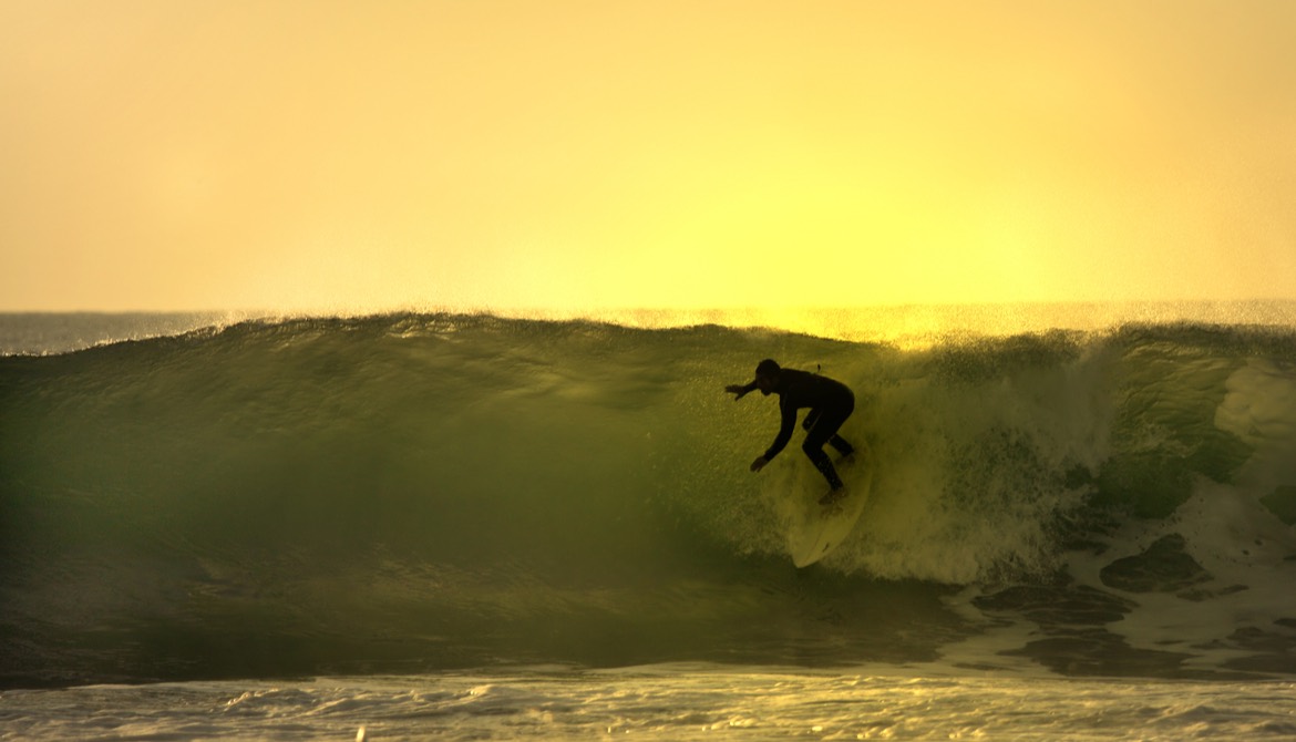 surfer catching a wave at sunset