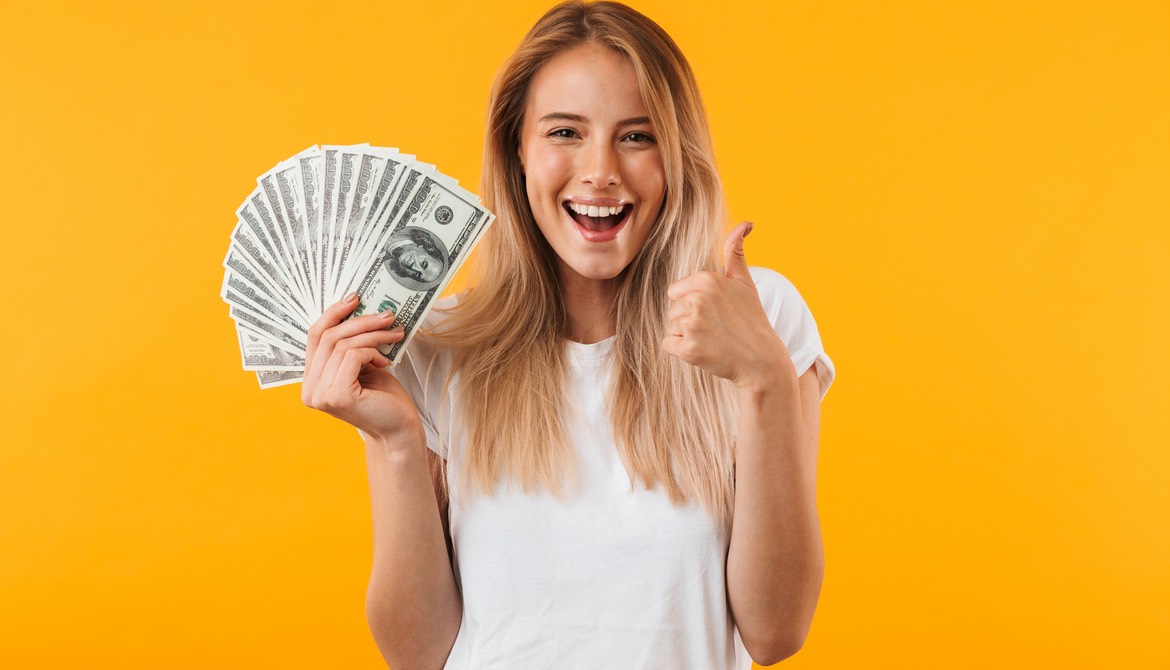 woman on a yellow background holding fanned out money