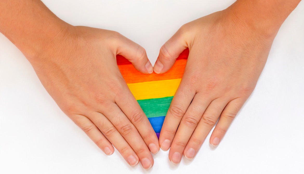hands forming a heart over a rainbow