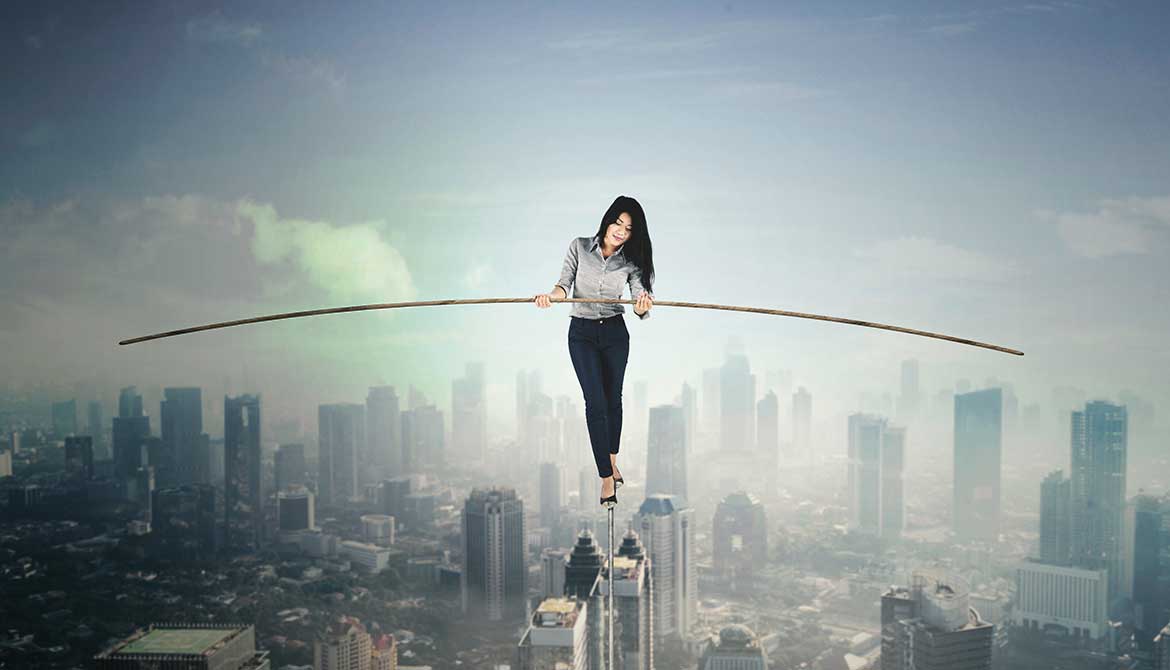 businesswoman holding a stick to balance while walking on a tightrope above a city