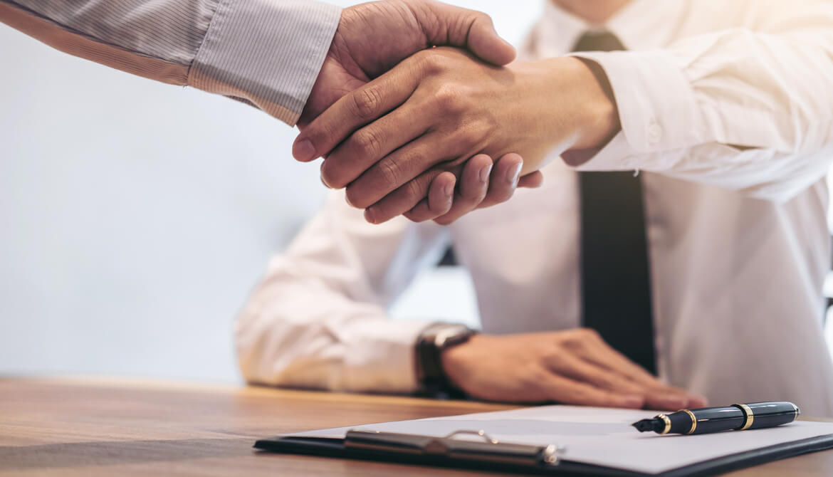 executives shake hands over a contract