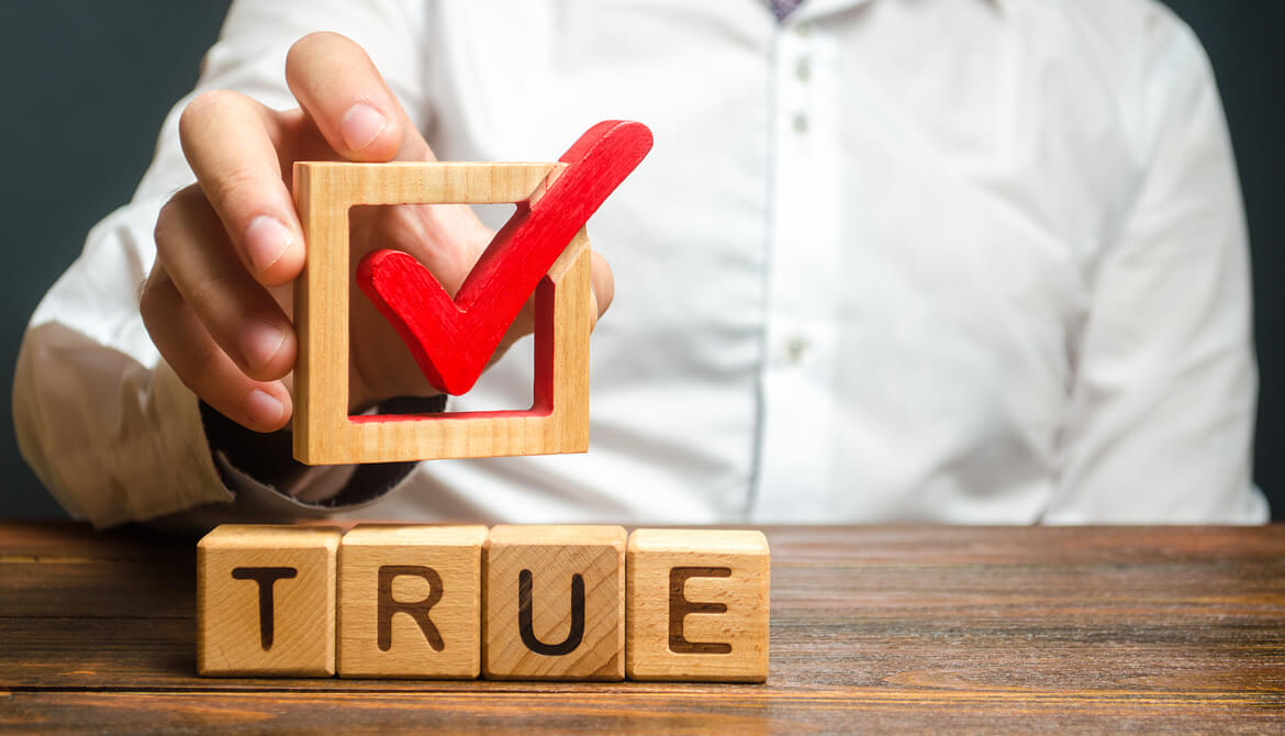 man holds red check mark over the word true