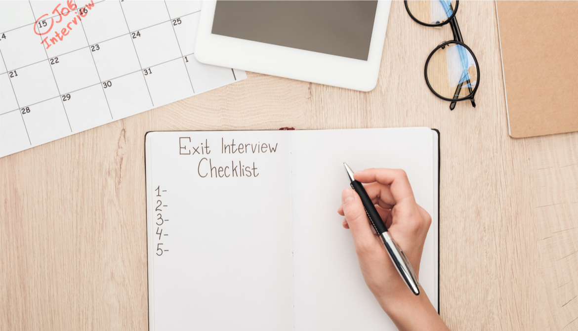 partial view of recruiter holding pen near notebook with exit interview checklist lettering