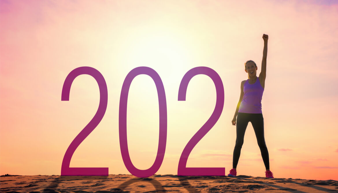 woman with arm up and fist next to a 2021 sign in the sun
