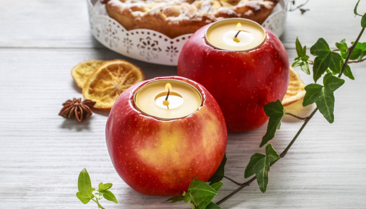 tea candles set into hollowed out apples sitting on a white wood table in front of a pie