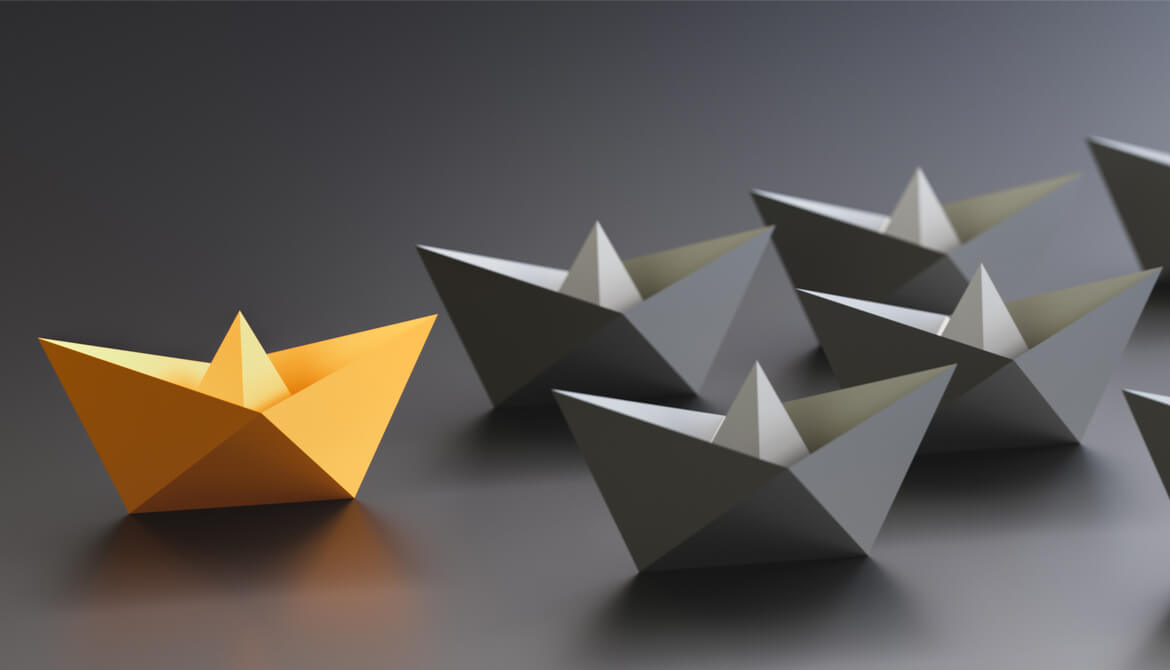 yellow paper boat leading black paper boats