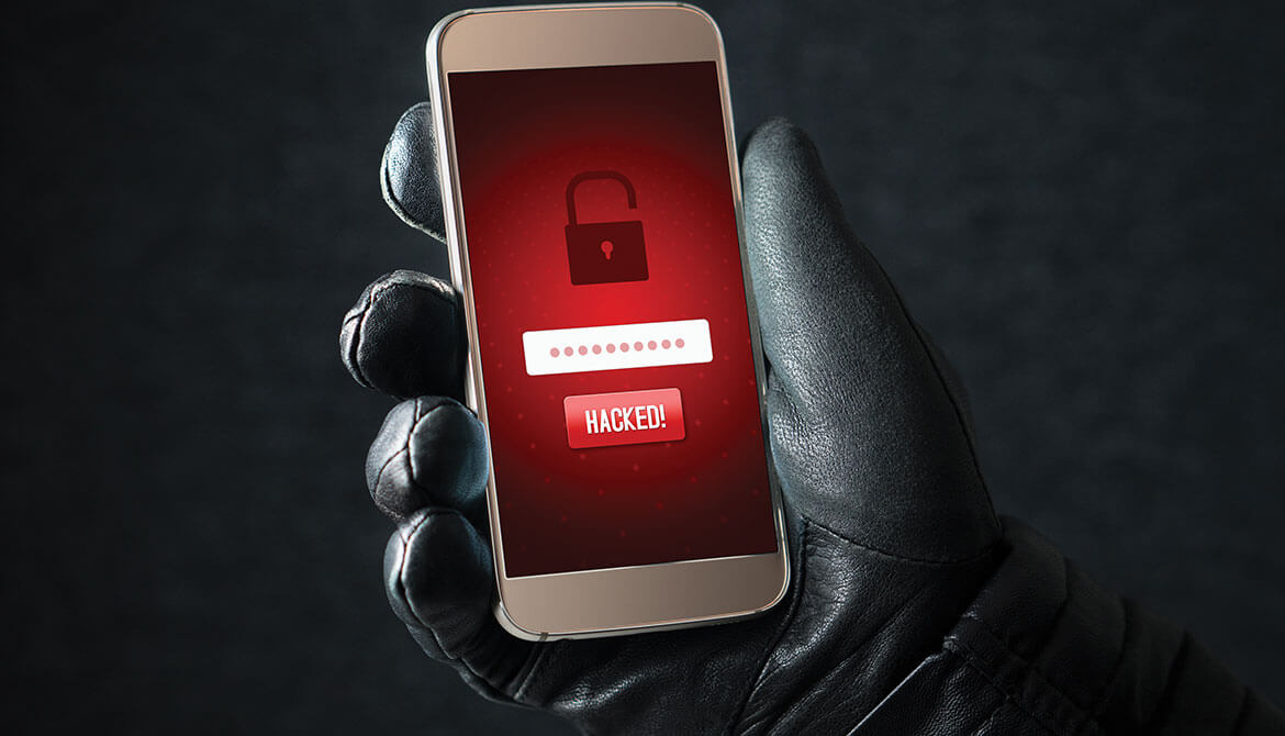 black leather gloved hand holds up smartphone with red screen depicting an open padlock and the word hacked